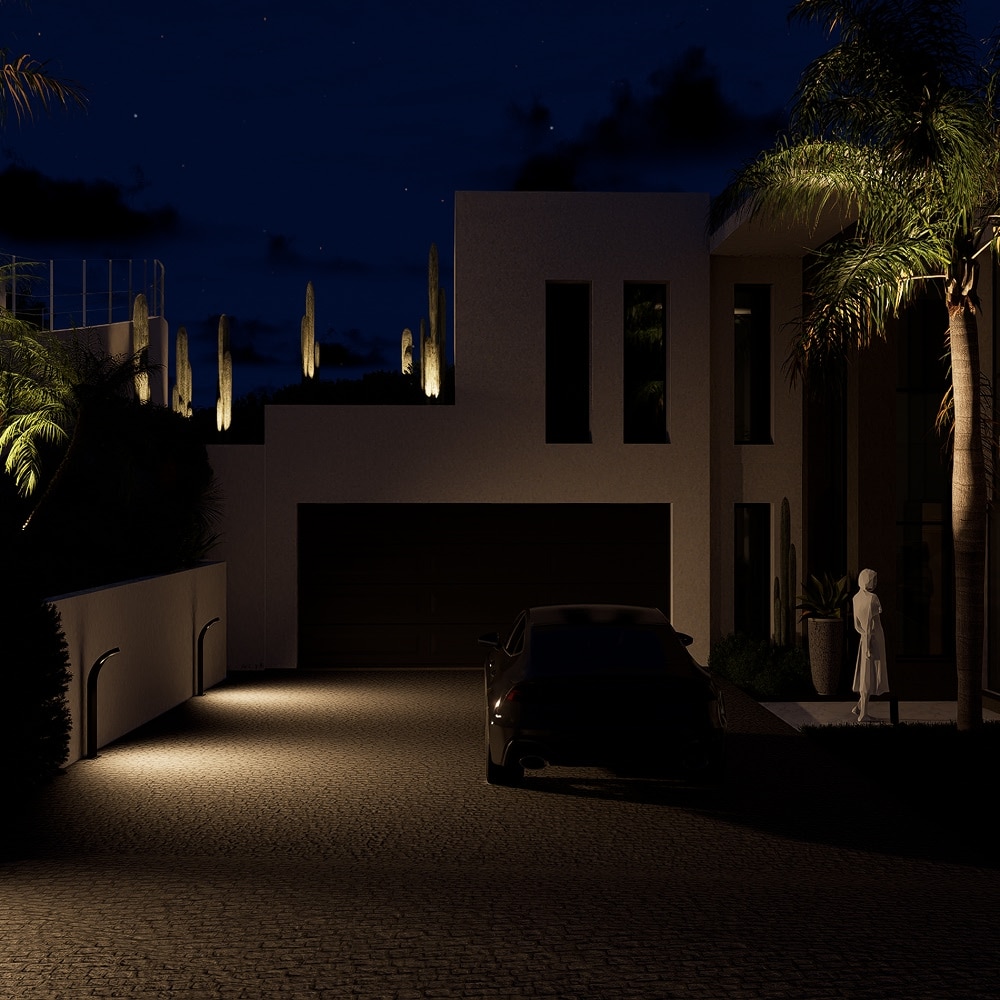 Maison moderne de nuit avec allée pavée éclairée, voiture noire et palmiers sous un ciel étoilé.