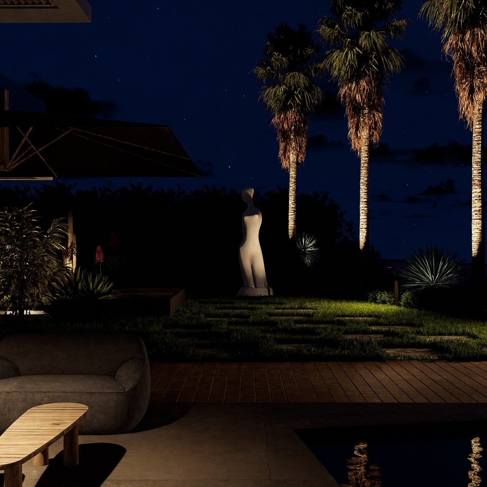 Terrasse de luxe de nuit avec piscine, palmier éclairé, statue blanche et mobilier design sur un gazon soigné.